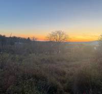 RD TVRDOMESTICE, pozemkom s prístupom z oboch strán - Západ slnka nad pokojným prírodným prostredím v Tvrdošmesticiach, jemne osvetľujúc rodinné domy.