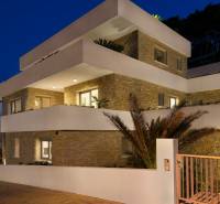 KRÁSNA MODERNÁ VILA  /400 m²/ s výhľadom na more, ostrov BRAČ - Exteriér Vily v meste Bol so svetlými terasami a kamennými stenami za súmraku.