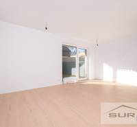 2-izbový byt s predzáhradkou 135 m² a parkovaním v tichej časti BA - Svetlá obývacia izba s podlahou s dreveným dekorom a veľkým oknom v 2-izbovom byte.