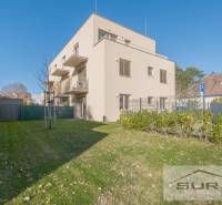 2-izbový byt s predzáhradkou 135 m² a parkovaním v tichej časti BA - Budova s dvomi poschodiami, zelená tráva a modrá obloha na Železničnej ulici v Bratislave.