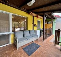 Na predaj rekreačná chata s pozemkom, Domaša, Valkov - Veranda chaty na Trnkovej 213, Bžany, so sivou pohovkou a dlažbou.