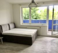 PRENÁJOM 1i byt s Loggiou, Tomášikova ul., Ružinov - Svetlá izba s posteľou, otvoreným balkónom a podlahou s dreveným dekorom.