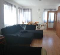 EXKLUZÍVNE, VEĽKÝ RODINNÝ DOM NECPALY - Obývacia izba s čiernou sedačkou, jedálenským stolom a množstvom prirodzeného svetla.