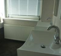 EXKLUZÍVNE, VEĽKÝ RODINNÝ DOM NECPALY - Kúpeľňa rodinného domu s dvomi umývadlami, radiátorom a oknom s žalúziami.