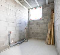 Rodinný dom Hontianske Tesáre - Nezariadená miestnosť s betónovými stenami a podlahou, pripravená na inštalácie v rodinnom dome.