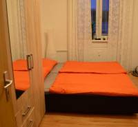 PRIESTRANNÝ 2-IZB BYT V UZAVRETOM AREÁLI, MIEROVÁ KOLÓNIA, NOVÉ MESTO - Spálňa v 2-izbovom byte s posteľou, šatníkom a podlahou s dreveným dekorom.