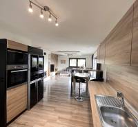 Rodinný dom v obci Dubová s 920m2 rozsiahlym pozemkom  - Kuchyňa v rodinnom dome s podlahou s dreveným dekorom a praktickým sedením.