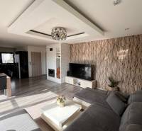 Rodinný dom v obci Dubová s 920m2 rozsiahlym pozemkom  - Obývacia izba v Rodinnom dome s pohovkou, TV a krbom, podlaha s dreveným dekorom.