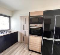 Rodinný dom v obci Dubová s 920m2 rozsiahlym pozemkom  - Kuchyňa v rodinnom dome s plynovým sporákom a spotrebičmi, podlaha s dreveným dekorom.