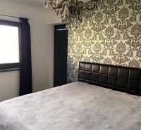 Rodinný dom v obci Dubová s 920m2 rozsiahlym pozemkom  - Spálňa v rodinnom dome s dekoratívnou tapetou a lustrom. Symfónia interiérového dizajnu.