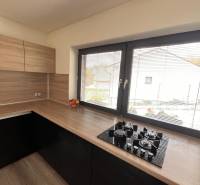 Rodinný dom v obci Dubová s 920m2 rozsiahlym pozemkom  - Kuchyňa s dreveným dekorom a pultom v rodinnom dome, s oknom a plynovým varičom.