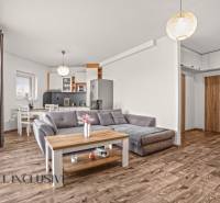 NA PREDAJ 2-IZBOVÝ BYT S 2 BALKÓNMI, DUNAJSKÁ STREDA - Obývacia izba 2-izbového bytu s pohovkou a podlahou s dreveným dekorom.