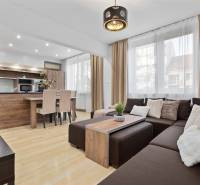 PREDAJ-2 IZBOVÝ BYT-KOMPLETNÁ REKONŠTRUKCIA - RUŽINOV - Obývačka s podlahou s dreveným dekorom v 2-izbovom byte s rohovou sedačkou a kuchyňou.