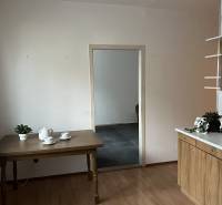 REZERVOVANÝ! Na predaj 2izbový byt v meste Senica - Kuchyňa v 2-izbovom byte s podlahou v drevenom dekore, stolom a riadom.