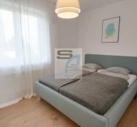 2-izbový byt s terasou 15 m² a parkovaním v tichej časti Bratislavy - Spálňa s veľkou posteľou, záclonami a podlahou s dreveným dekorom v 2-izbovom byte.