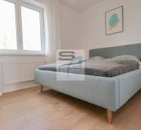 2-izbový byt s terasou 15 m² a parkovaním v tichej časti Bratislavy - Spálňa v 2-izbovom byte, svetlá posteľ, podlaha s dreveným dekorom, jednoduchý dekor.