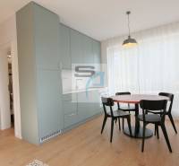 2-izbový byt s terasou 15 m² a parkovaním v tichej časti Bratislavy - Jedálenský kút so stolom a stoličkami, zabudovanými skrinkami a podlahou s dreveným dekorom.