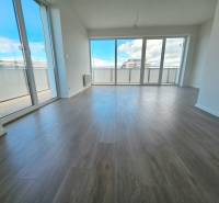 3i. BYT S VLASTNÝM TEP. ČERPADLOM + KLIMATIZÁCIA A EXTERIÉROVÉ ŽALÚZIE - Priestranná obývačka s veľkými oknami a drevenou podlahou v 3-izbovom byte.