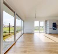 3i. BYT SO ZÁHRADOU +TEP. ČERPADLO, KLIMATIZÁCIA A ŽALÚZIE V CENE - Svetlý priestor v 3-izbovom byte s veľkými oknami a minimalistickou kuchyňou.