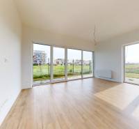 3i. BYT SO ZÁHRADOU +TEP. ČERPADLO, KLIMATIZÁCIA A ŽALÚZIE V CENE - Priestranný obývací priestor s drevenou podlahou a veľkými oknami v 3-izbovom byte.