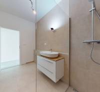 3i. BYT SO ZÁHRADOU +TEP. ČERPADLO, KLIMATIZÁCIA A ŽALÚZIE V CENE - Kúpeľňa v 3-izbovom byte s umývadlom, sprchou a otvorenými dverami.