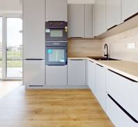 3i. BYT SO ZÁHRADOU +TEP. ČERPADLO, KLIMATIZÁCIA A ŽALÚZIE V CENE - Kuchyňa v 3-izbovom byte so vstavanými spotrebičmi a výhľadom na terasu.