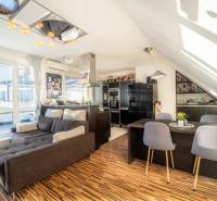 Rezervovaný!!! 2izb + terasa byt Vajanského Modra 93,8m2 - Obývačka s kuchyňou v 2-izbovom byte s podlahou s dreveným dekorom a pohodlnou sedačkou.