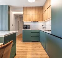 PRENÁJOM 3 izbový byt s predzáhradkou, BORY PROMENÁDA - Kuchyňa v 3-izbovom byte s podlahou s dreveným dekorom a zelenými skrinkami.