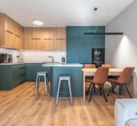 PRENÁJOM 3 izbový byt s predzáhradkou, BORY PROMENÁDA - Kuchyňa v 3-izbovom byte s podlahou s dreveným dekorom a jedálenským stolom.