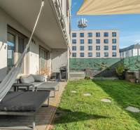 PRENÁJOM 3 izbový byt s predzáhradkou, BORY PROMENÁDA - Záhradná terasa pri 3-izbovom byte v Bratislave - Lamači, Jána Langoša, s trávnikom a závesmi.