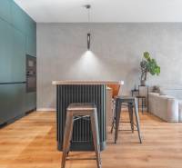 PRENÁJOM 3 izbový byt s predzáhradkou, BORY PROMENÁDA - Kuchyňa v 3-izbovom byte s ostrovčekom, kovovými stoličkami a podlahou s dreveným dekorom.