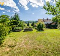 Na predaj: Rodinný dom Slatinské Lazy s očarujúcou atmosférou - Záhrada rodinného domu v Slatinských Lazoch s trávnikom a výsadbou, obklopená stromami.