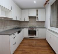 MODERNÝ, KOMPLETNE PREROBENÝ 3-IZB.BYT S LODŽIOU, OČOVÁ - Kuchyňa v 3-izbovom byte s bielymi skrinkami a podlahou s dreveným dekorom.