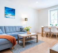 Na prenájom štýlový  3 - izb. byt  (Košice - Sever) - Obývacia izba v 3-izbovom byte so sedačkou a jedálenským stolom, podlaha s dreveným dekorom.