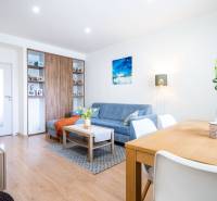 Na prenájom štýlový  3 - izb. byt  (Košice - Sever) - Obývacia izba v 3-izbovom byte s modrou sedačkou a podlahou s dreveným dekorom.