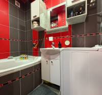 Na predaj: Investičný 3 izb.byt + murovaná PIVNICA - Kúpeľňa v 3-izbovom byte s červenými a sivými obkladmi, vaňou a práčkou.