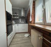Na predaj: Investičný 3 izb.byt + murovaná PIVNICA - Kuchyňa v 3-izbovom byte s bielymi skrinkami, tehlovým obkladom a veľkým oknom.