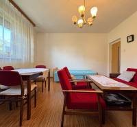 Na predaj: Rodinný dom v meste Levice - Obývacia izba v rodinnom dome s červeným nábytkom a podlahou s dreveným dekorom.