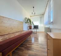 Na predaj: Rodinný dom v meste Levice - Izba v rodinnom dome s posteľou, televíziou a podlahou s dreveným dekorom.