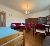 Na predaj: Rodinný dom v meste Levice - Obývacia izba v rodinnom dome s podlahou s dreveným dekorom, červeným nábytkom a knižnicou.