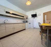 Na predaj: Rodinný dom v meste Levice - Kuchyňa v rodinnom dome s krémovými skrinkami, jedálenským stolom a nenápadným dekorom.