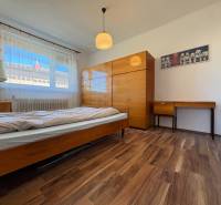 Na predaj: Rodinný dom v meste Levice - Spálňa s podlahou s dreveným dekorom, posteľou a nábytkom v rodinnom dome.