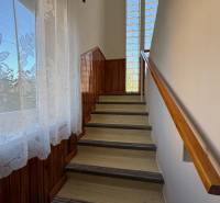Na predaj: Rodinný dom v meste Levice - Schodisko s dreveným obkladom a zábradlím, veľké okno s kvetinovým závesom.