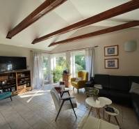 PREDAJ krásny 6 izb. rod. dom prepojený s prírodou - Obývacia izba s trámovým stropom, dlažbou, čiernou sedačkou a výhľadom do záhrady v rodinnom dome.