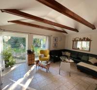 PREDAJ krásny 6 izb. rod. dom prepojený s prírodou - Obývačka v rodinnom dome s výhľadom do záhrady, trámový strop, čierna sedačka.