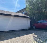 PREDAJ krásny 6 izb. rod. dom prepojený s prírodou - Brána do garáže pri rodinnom dome v Lehote, vedľa je zaparkované červené auto.