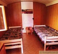 Chata nad kúpeľmi Dudince s vlastným pozemkom - Drevený interiér chaty s dvoma lôžkami a podlahou s dreveným dekorom.