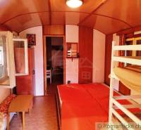 Chata nad kúpeľmi Dudince s vlastným pozemkom - Interiér chaty s poschodovou posteľou, podlahou s dreveným dekorom a otvoreným oknom.