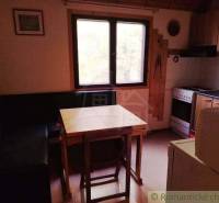 Chata nad kúpeľmi Dudince s vlastným pozemkom - Kuchynka v chate s rohovou lavicou, stolom a sporákom.