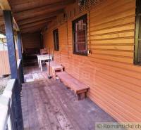 Chata nad kúpeľmi Dudince s vlastným pozemkom - Chata v Dudinciach s verandou z podlahou s dreveným dekorom a lavičkou.